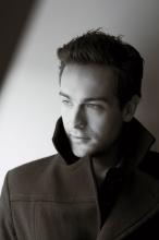 Black and white photo of Tom Mison in a pea coat with collar popped